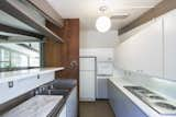 Kitchen, Pendant Lighting, Cooktops, Drop In Sink, Refrigerator, and Wall Oven A streamlined, white kitchen.  Photos from Own This L.A. Midcentury by A. Quincy Jones For $2.45M