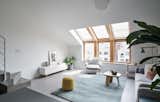 Living Room, Coffee Tables, Sofa, Chair, Rug Floor, Ceiling Lighting, Floor Lighting, Console Tables, and Concrete Floor Large wood-framed windows with multi-plane glass help bring more light into the interiors. 

  Photos from A Loft Mezzanine Cleverly Enlarges This Small Beijing Flat