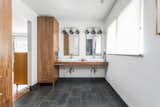 Bath Room, Wood Counter, Wall Mount Sink, and Slate Floor "Our bathroom cabinets were really the biggest success for us. With all the medical supplies, we needed extra storage in the bathroom. We had a very specific vision in mind, which Duvall Woodworking knocked out of the park," says LeAnne.

  Photos from Before & After: A 1952 Midcentury Becomes a Wondrous, Wheelchair-Accessible Home