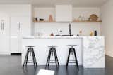 Kitchen, White, Subway Tile, Concrete, Refrigerator, and Marble A continuous open-plan living, kitchen, and dining area with a powder room is located in the living level.   Kitchen Subway Tile White Refrigerator Marble Concrete Photos from A Tiered Home in Los Angeles Hugs a Steep Slope