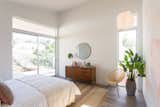 Bedroom, Chair, Dresser, Bed, Medium Hardwood, Pendant, and Rug The bedrooms have access to the spacious deck outdoors.  Bedroom Pendant Medium Hardwood Dresser Rug Photos from A Tiered Home in Los Angeles Hugs a Steep Slope