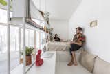 Bedroom, Bookcase, Storage, Shelves, Bed, Concrete, and Wall The sleeping and study nook sit on a raised platform, and are surrounded by open shelving filled with books and plants.     Bedroom Wall Concrete Bookcase Photos from A Perforated Balcony Brings Ample Light Into a Tiny Abode
