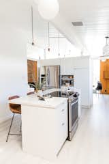 Kitchen, White Cabinet, Refrigerator, Cooktops, Range, Marble Counter, Pendant Lighting, Microwave, Undermount Sink, and Light Hardwood Floor Hong elevated the new IKEA kitchen with white slab fronts from Semihandmade.  Photos from Budget Breakdown: A Cramped Eichler Kitchen Gets a $49K Refresh