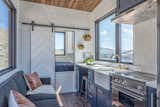 The water tank is stored in the space under the bed. The propane cooktop has a fold-down cover to allow for more counter space when needed. 

  Tolix Marai Counter Stool from Grab This Adventure-Ready Tiny Home For Less Than $54K