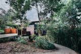 Outdoor, Small, Woodland, Trees, Wood, Vertical, Walkways, Wood, Shrubs, Side Yard, and Slope The home's low-maintenance Cor-Ten steel exterior can be easily washed down when needed.  Outdoor Side Yard Slope Vertical Woodland Wood Small Photos from A Tiny Guesthouse Hides in a Lush Australian Rainforest