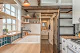 Kitchen, Recessed, Wall Oven, Medium Hardwood, Wood, Ceramic Tile, White, Drop In, and Pendant The ladder to the loft can be slid to the side when not in use. 

  Kitchen Wall Oven Ceramic Tile White Recessed Wood Photos from This Canadian Tiny Home Beams a Rustic, West Coast Vibe