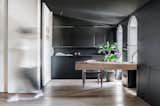 A sparse wooden desk and ample black cabinetry are elements that can be used as modern home office ideas. Vibrant natural light floods the room with light despite the dark background in this expansive modern home office in a heritage apartment in Kiev.