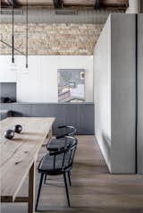 Dining Room, Table, Chair, Pendant Lighting, Storage, and Medium Hardwood Floor Artwork by Ukrainian artist Artem Prut.  Photos from A Monochromatic Palette Unifies Old and New in This Ukrainian Bachelor Pad