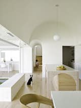 Kitchen, White Cabinet, Pendant Lighting, Light Hardwood Floor, and Subway Tile Backsplashe In the kitchen, which functions as the heart of the house, the architects have created a geometrically pure, double-height barrel vault. 

  Photo 11 of 16 in An Australian Home Relishes Sunshine With a New Extension