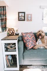 Living Room, Sofa, Shelves, Vinyl Floor, Table Lighting, Lamps, End Tables, Dark Hardwood Floor, and Rug Floor Dark wood contrasts with white walls, and adds a natural touch.  Photo 10 of 21 in Before & After: Augustine the Airstream Gets a Chic DIY Makeover