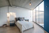 Bedroom, Night Stands, Bed, Table Lighting, Light Hardwood Floor, and Pendant Lighting From the glass wall of the master bedroom, the user can look down into the living lounge.

  Photo 10 of 14 in Extruded Red Bricks Create a Gorgeous, Geometric Mexican Home