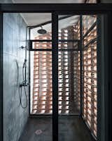 Sunlight enters the shower area through the gaps between the bricks.