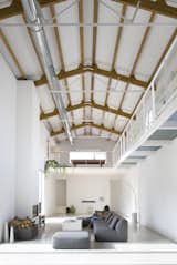 The wooden beams on the ceiling have been left exposed to add warmth and color to the otherwise simple white color scheme.