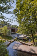 The new construction relates with the land in a very spontaneous way, taking advantage of its steep slope, the small stream, and the extraordinary view of the landscape.  Photo 3 of 15 in Two Ponds Bookend This Concrete-and-Wood Residence in Portugal