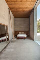 Bedroom, Bed, Bench, and Concrete Floor An elongated master bedroom.  Photo 11 of 15 in Two Ponds Bookend This Concrete-and-Wood Residence in Portugal