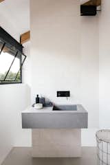 Bath Room, Concrete Floor, Engineered Quartz Counter, Vessel Sink, Ceramic Tile Wall, and Drop In Sink A look at the simple, modern bathroom with a monolithic sink.

  Photos from A South African Architect Designs an Off-Grid, Modern Home For Her Parents