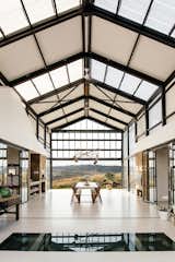 Dining Room, Table, Pendant Lighting, Concrete Floor, Chair, Storage, Ceiling Lighting, and Shelves The wine cellar can be seen through the glass section of the floor.  Photo 9 of 18 in A South African Architect Designs an Off-Grid, Modern Home For Her Parents