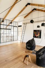 Living Room, Stools, Chair, Light Hardwood Floor, and Pendant Lighting A versatile leisure room connects to a fully-glazed study and work room.

  Photos from A South African Architect Designs an Off-Grid, Modern Home For Her Parents