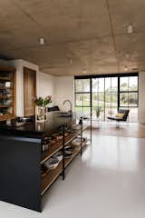 Kitchen, Undermount, Wood, Ceiling, Concrete, Metal, and Open The industrial use of building materials continues to the interior closets, cupboards, and kitchen area. 

  Kitchen Ceiling Open Wood Photos from A South African Architect Designs an Off-Grid, Modern Home For Her Parents