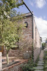 From the garden, the new extension was designed as a pair of interlocking volumes—a pitched, timber-clad wing that overlaps a smaller mass of salvaged brick.&nbsp;