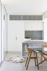 An open-plan kitchen and dining area within the addition feature white cabinets.