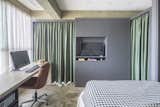 Green curtains in the gray cabinet and partition provide privacy for the bedroom and work space.