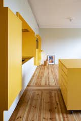 A bright, yellow "function wall" saves space and visually expands this compact apartment.