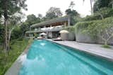 Sited on a steep hill overlooking lush tropical jungle and a river, this private villa is set on different levels that appear as if they are part of the natural landscape. The architecture follows the contours of the land, allowing for in-between spaces and gardens that would otherwise be difficult to enjoy.