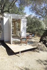 Outdoor, Side Yard, Small Patio, Porch, Deck, Trees, Wood Patio, Porch, Deck, and Decking Patio, Porch, Deck The large external door to the end of the house is solid timber.  Photo 1 of 10 in A Yoga Teacher’s Tiny Home on Wheels Goes Off-Grid in Greece
