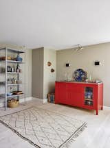 A red kitchenette by Københavns Møbelsnedkeri dominates the space, tempered by a more neutral Beni Ouarain rug. The storage rack in lavender is by HAY.