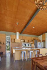 At sunrise, light bounces off the rammed earth wall, imbuing the kitchen with a warm, orange glow at breakfast.    