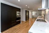Contemporary Sleek Black Kitchen with Built-in Appliances and Pot Filler