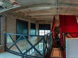 Custom built iron mezzanine with mahogany wood floors and a banister inspired by a 100-yr old Columbian bridge with inlaid tempered custom glass.