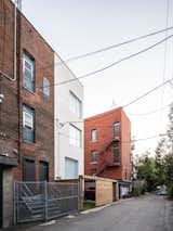 New white brick volume addition to the back alley landscape