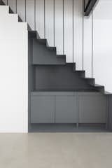 The steel staircase takes centre stage, conceived as a functional volume encasing an understair kitchen closet, whose main feature is its deep grey colour