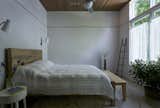 Bedroom with large window overlooking garden and slatted wood ceiling