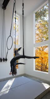 A 28-foot aerial studio is the heart of the home, facilitating movement and artistry while enabling physical and mental healing. The double-height windows emphasize the verticality of the space, and allow the clients to experience an intimate connection with nature while on the trapeze or lyra.