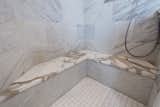 Book matched marble shower wall tiles and honed Calcutta marble seats to match the vanity countertops. 