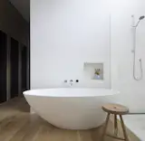 The walls are done in hand-troweled cement plaster that add to the monastic feel. Tub by Blu Bathworks. Shower head by Dornbracht. 