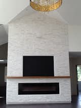 Quartz stacked white stone fireplace which stands 22 ft high with an exotic zebra wood mantel.  96" built in fireplace. 24" wide black and gold pendant, glimmering rings to the round gold finish canopy.