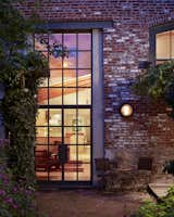 Trees, Back Yard, Flowers, Shrubs, Large Patio, Porch, Deck, Hardscapes, Gardens, Walkways, Exterior, Metal, Swing Door Type, Windows, and Picture Window Type A  steel window system infills the garden wall's existing masonry opening.  Photo 9 of 11 in Philadelphia Garden House by Wyant Architecture