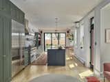Our design centered on the creation of a large kitchen that functions as the hub of the home. Two side-yard bay additions provide floor area for integral sitting and dining areas, while a folding window wall connects the space to a newly designed rear garden.