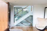 Beyond the custom glass wall in the family room is an open riser oak staircase, with glass guards and a wood handrail.