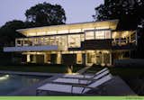 Outdoor, Large Pools, Tubs, Shower, Back Yard, Large Patio, Porch, Deck, Swimming Pools, Tubs, Shower, and Stone Patio, Porch, Deck the illuminated interior as the sun sets  Photo 8 of 14 in The Rosenblum Lakeside Residence by Stephen Midouhas Architect