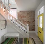 Entryway with original staircase and exposed brick exterior wall. 