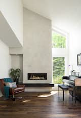 New living room fireplace, concrete finish facade, floating stone hearth, and wide plank natural walnut flooring. 