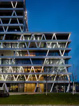 These occur at different heights through the principle of façade elements that are transposed against each other. The exterior image is characterized by a geometric structure consisting of slanting, steel-covered concrete pillars.