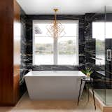 Black and gold Zebrino marble clad walls, Egyptian travertine floor tiles, Glacion free standing tub with Waterworks Atlas tub filler, Kelly Wearstler Cubist Chandelier and drinks table by Will Stone.