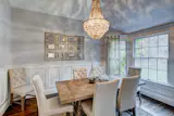 An intimate setting for entertaining or family dinners, this formal dining room is complete with an intricate chandelier, large wood table, and fabric chairs with metal accents.