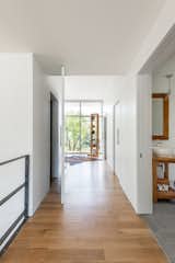 Hallway, Light Hardwood Floor, and Ceramic Tile Floor Hall to Master Suite w/ Custom Pivot Door  Photos from Spa Creek House